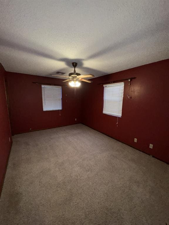 carpeted spare room with ceiling fan and a textured ceiling