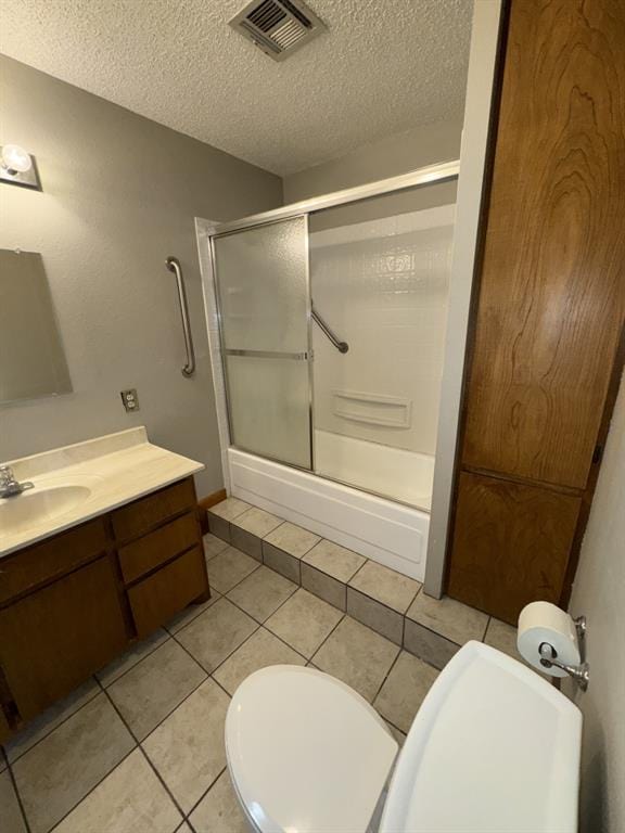 full bathroom featuring tile patterned floors, toilet, bath / shower combo with glass door, a textured ceiling, and vanity