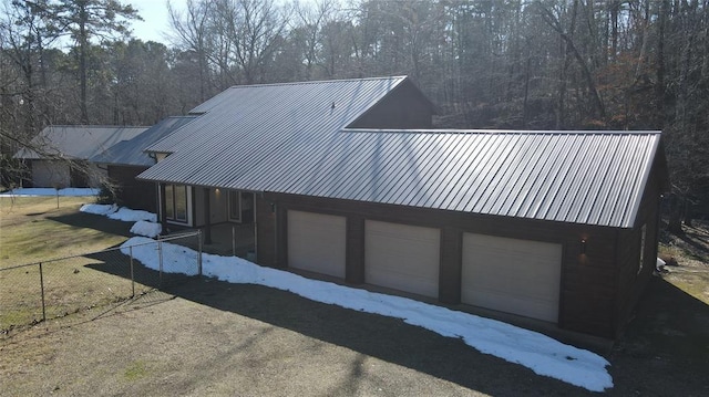 exterior space with metal roof, a view of trees, and fence