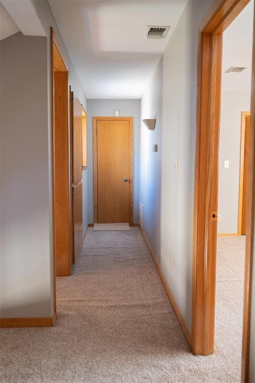 corridor with visible vents, baseboards, and light colored carpet