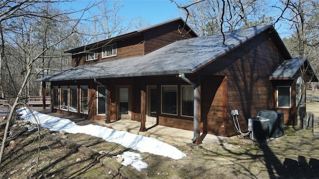 back of house with central AC unit, metal roof, and a sunroom