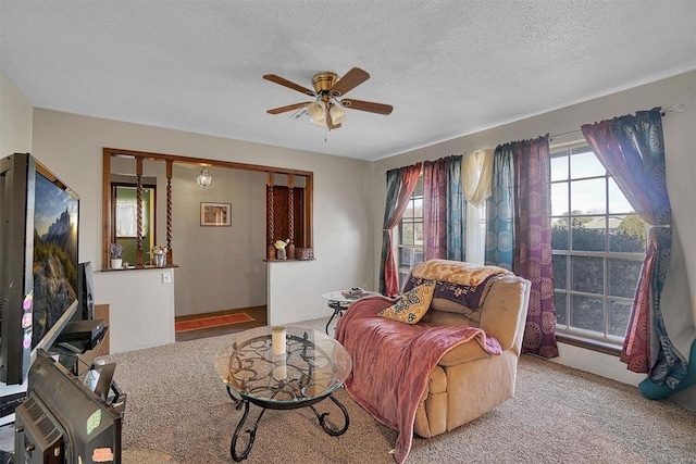 living room featuring ceiling fan, light colored carpet, and a textured ceiling