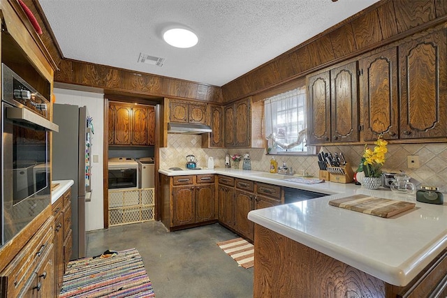 kitchen with sink, stainless steel fridge, white cooktop, washing machine and dryer, and a textured ceiling