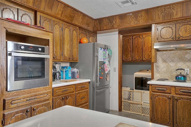 kitchen featuring tasteful backsplash, appliances with stainless steel finishes, and a textured ceiling