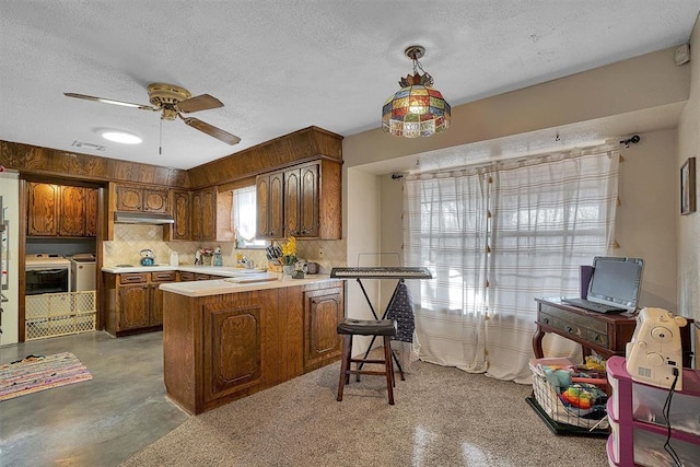 kitchen with a breakfast bar, hanging light fixtures, a textured ceiling, separate washer and dryer, and kitchen peninsula