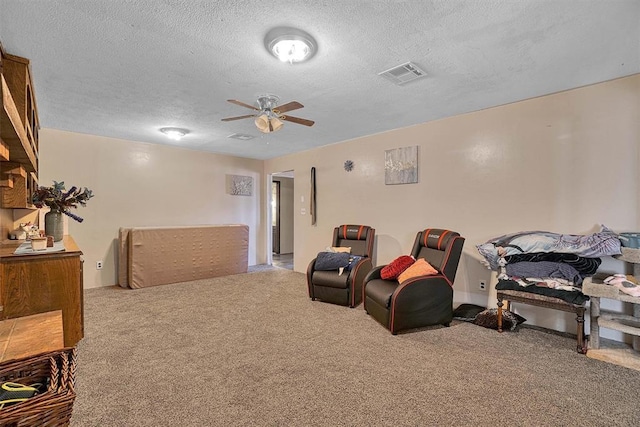 carpeted cinema with ceiling fan and a textured ceiling