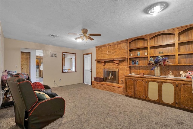 carpeted living room featuring ceiling fan, a fireplace, and a textured ceiling