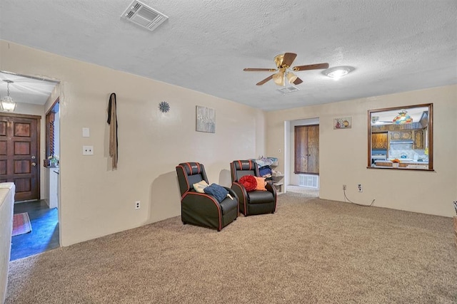 living area with ceiling fan, carpet flooring, and a textured ceiling