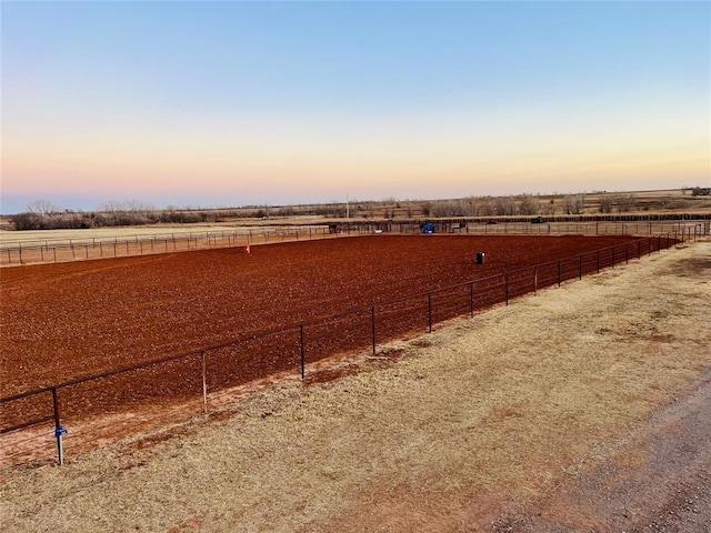 yard at dusk featuring a rural view