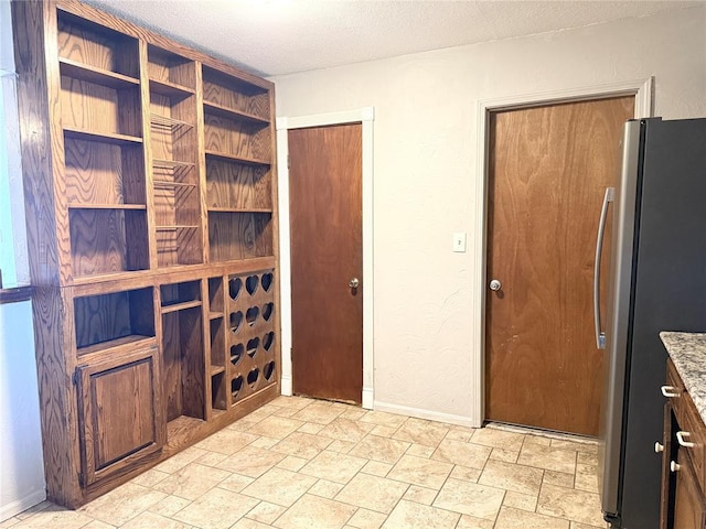 wine room with a textured ceiling, baseboards, and stone finish flooring