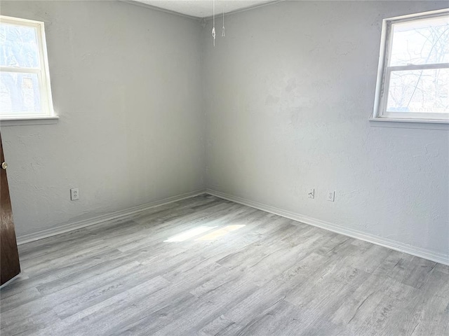 spare room featuring wood finished floors, baseboards, and a textured wall