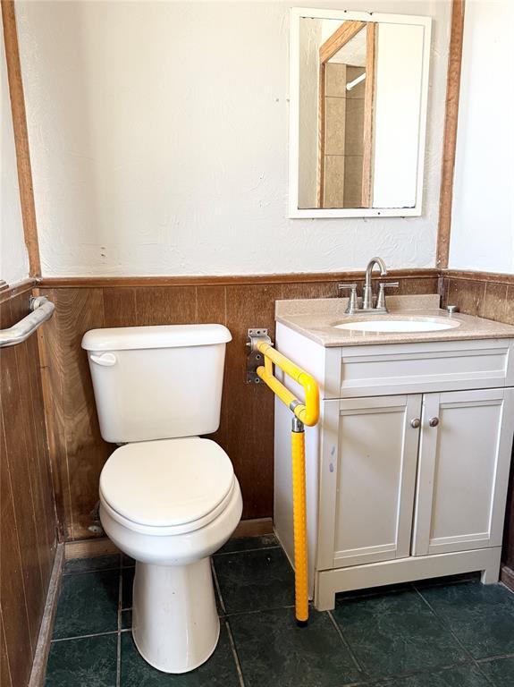 bathroom featuring tile patterned floors, wainscoting, toilet, and vanity