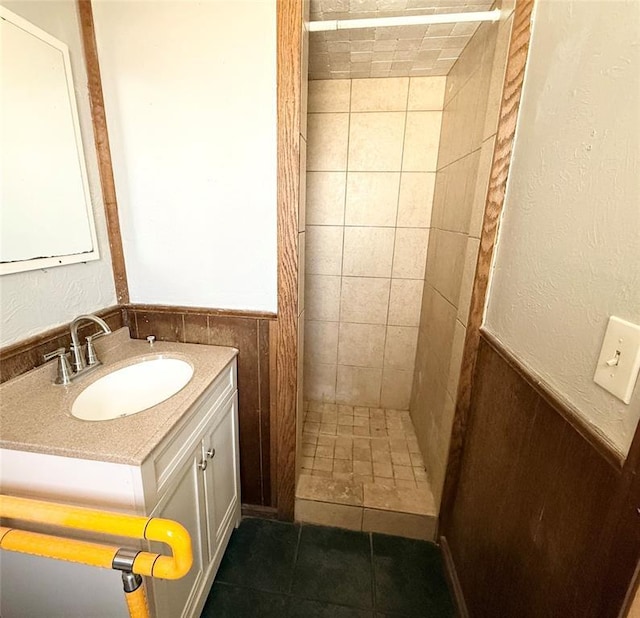 full bath with a tile shower, tile patterned flooring, vanity, and a textured wall