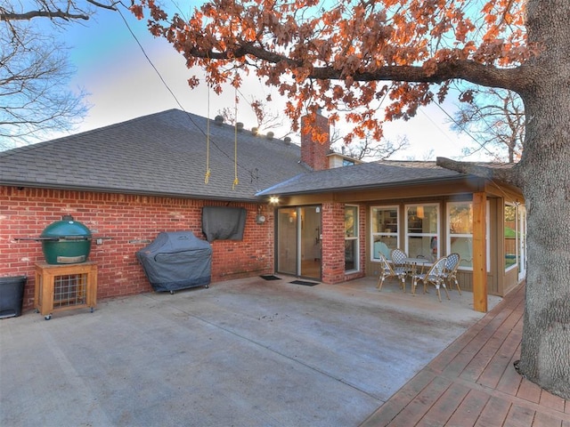 back house at dusk with a wooden deck and a patio area