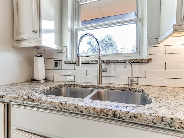 kitchen featuring sink, light stone counters, and decorative backsplash