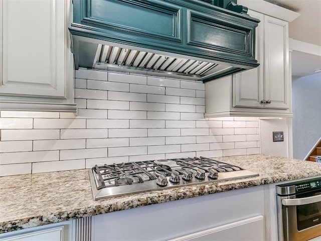 kitchen with premium range hood, appliances with stainless steel finishes, decorative backsplash, and white cabinets