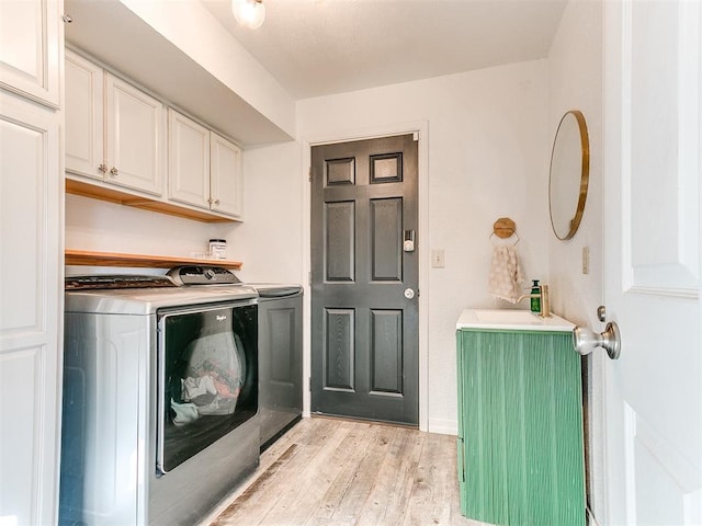 laundry room featuring cabinets, light hardwood / wood-style floors, and washing machine and dryer