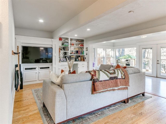 living room featuring french doors, built in features, and light hardwood / wood-style flooring