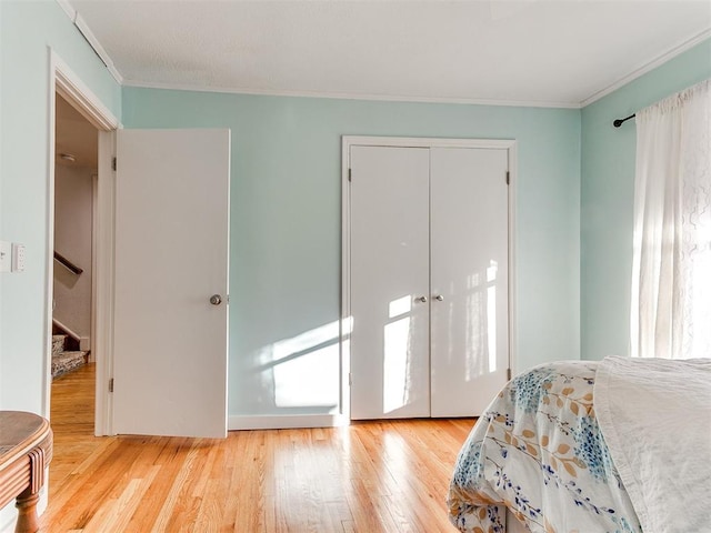 bedroom featuring crown molding, light hardwood / wood-style floors, and a closet