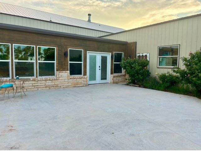 back house at dusk featuring a patio and french doors