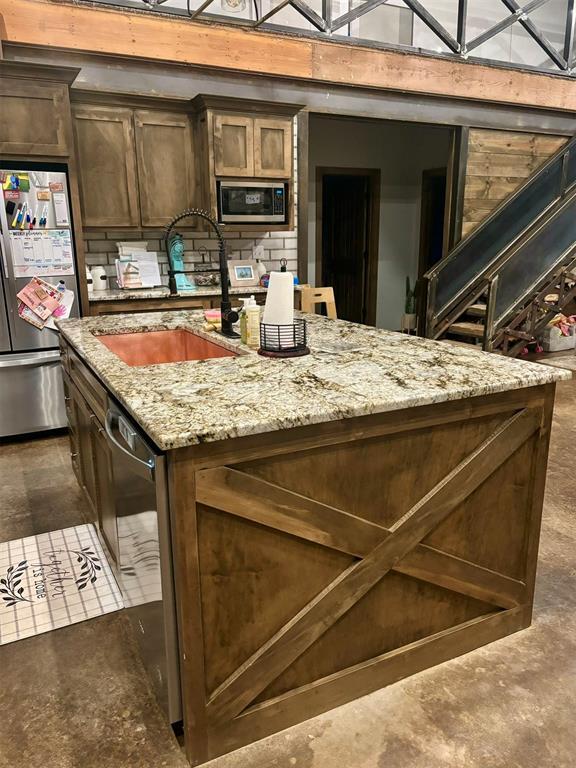 kitchen featuring lofted ceiling, sink, dark brown cabinets, stainless steel appliances, and light stone countertops