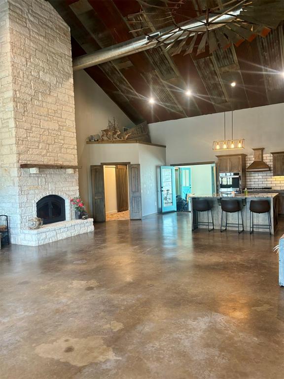 unfurnished living room featuring a fireplace and high vaulted ceiling