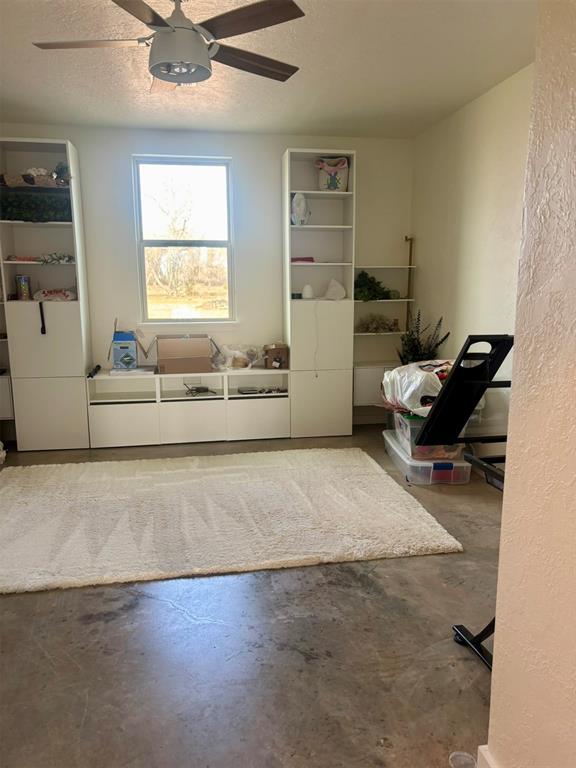 interior space featuring a textured ceiling, concrete flooring, and ceiling fan