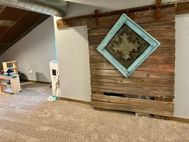 interior space with vaulted ceiling, a barn door, and carpet floors