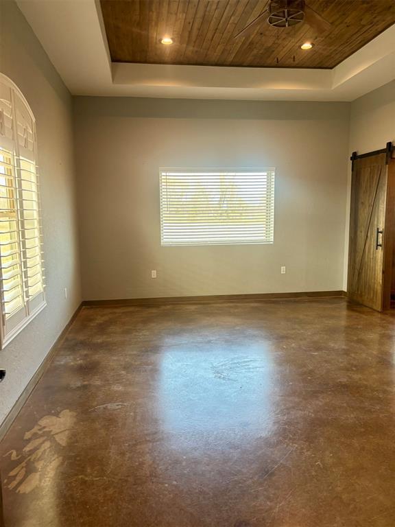 spare room featuring a raised ceiling, ceiling fan, a barn door, and wood ceiling