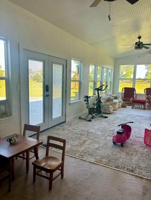 sunroom / solarium with lofted ceiling, ceiling fan, and french doors