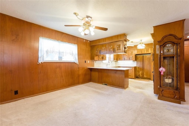 kitchen featuring light carpet, wood walls, and kitchen peninsula