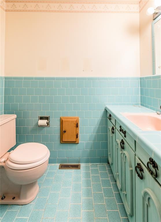 bathroom featuring vanity, toilet, tile patterned flooring, and tile walls