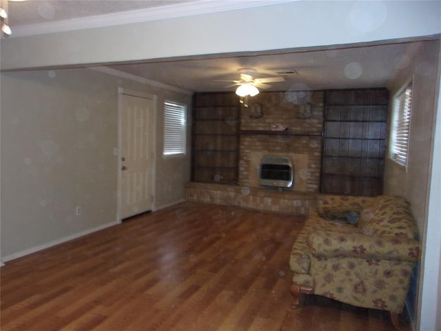 living room featuring ceiling fan, hardwood / wood-style floors, heating unit, a fireplace, and ornamental molding