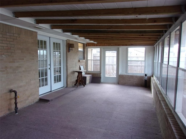 unfurnished sunroom featuring beamed ceiling and french doors