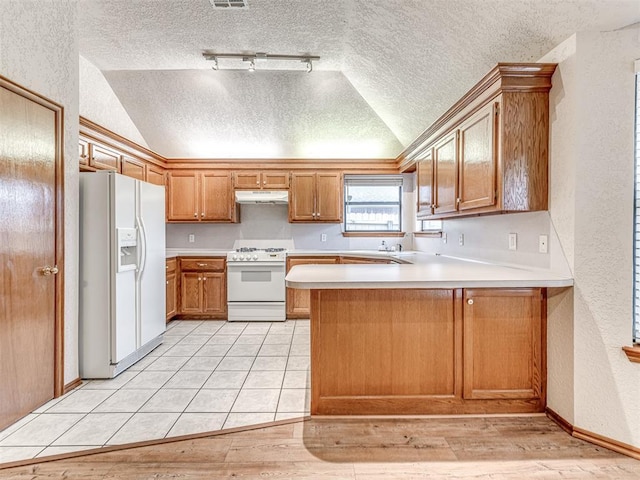 kitchen featuring lofted ceiling, white appliances, kitchen peninsula, and a textured ceiling