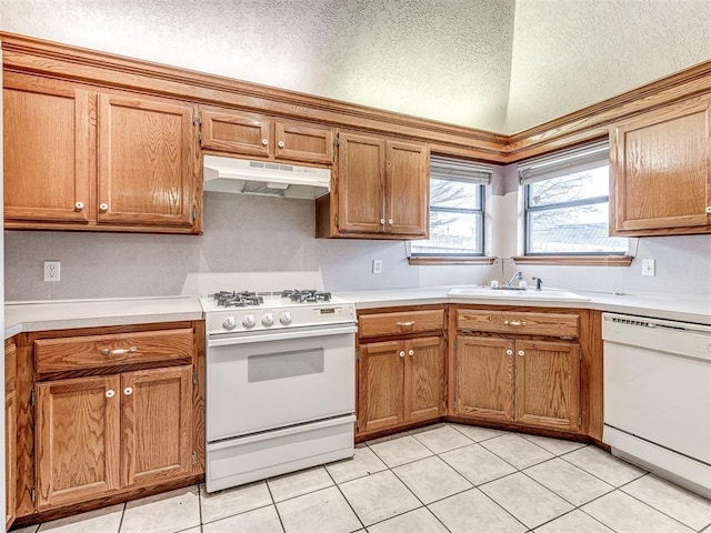 kitchen with sink, white appliances, light tile patterned floors, and a textured ceiling