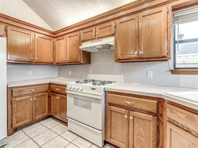 kitchen with white appliances, vaulted ceiling, a textured ceiling, and light tile patterned floors