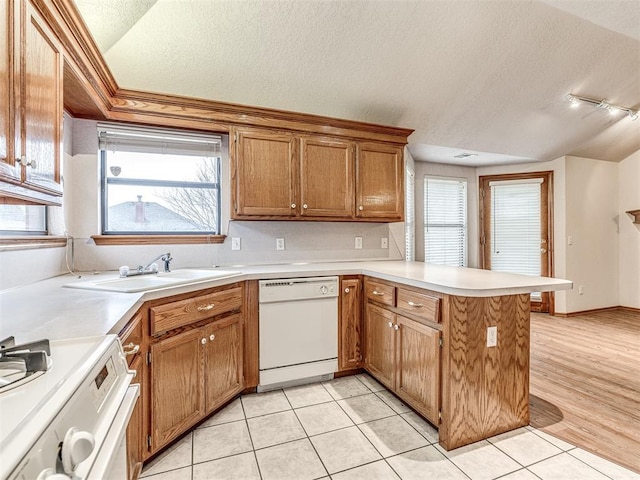 kitchen with lofted ceiling, sink, a textured ceiling, kitchen peninsula, and white appliances