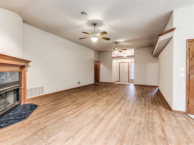 unfurnished living room featuring a tiled fireplace, lofted ceiling, ceiling fan, and light wood-type flooring