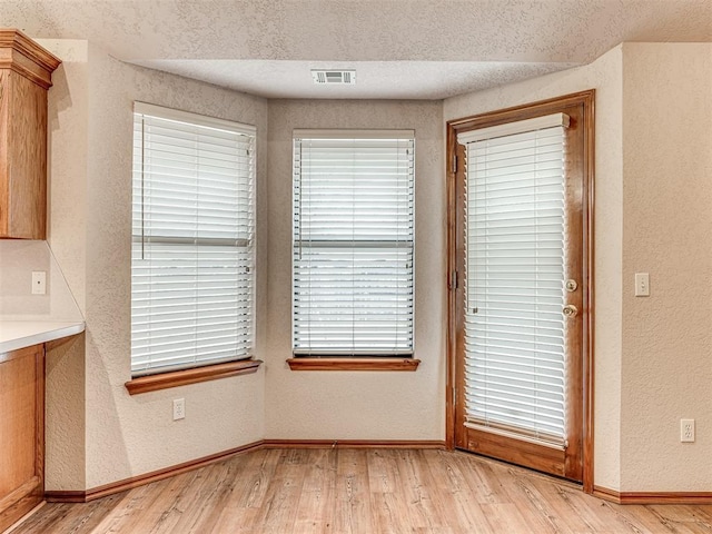 unfurnished dining area featuring light hardwood / wood-style floors and a textured ceiling