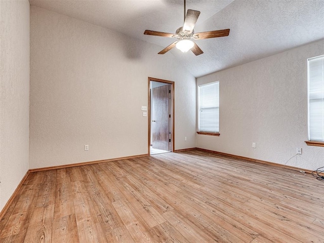 unfurnished room with a healthy amount of sunlight, vaulted ceiling, light hardwood / wood-style floors, and ceiling fan