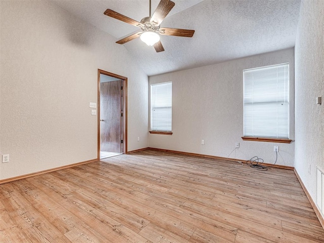 spare room featuring a textured ceiling, vaulted ceiling, light hardwood / wood-style floors, and ceiling fan