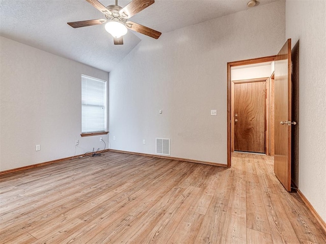 spare room with ceiling fan, lofted ceiling, and light wood-type flooring