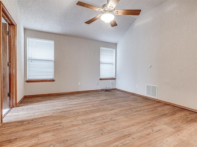 empty room with ceiling fan, a wealth of natural light, light hardwood / wood-style floors, and a textured ceiling