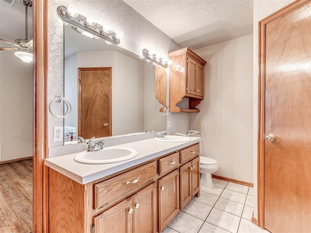 bathroom with vanity, ceiling fan, toilet, tile patterned floors, and a textured ceiling