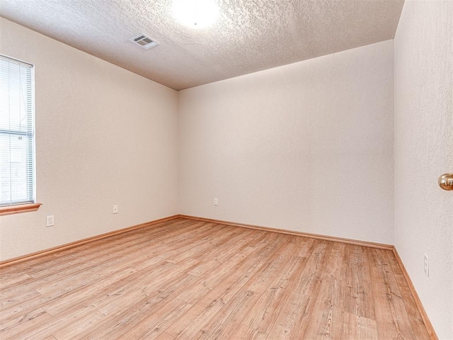 empty room featuring a textured ceiling and light wood-type flooring