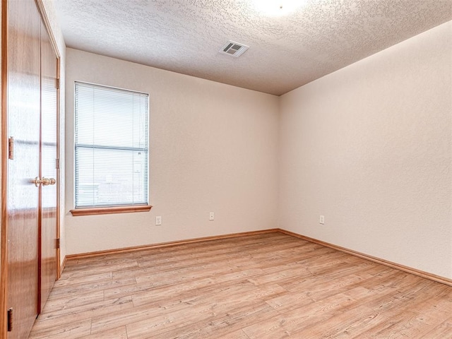 empty room featuring light hardwood / wood-style flooring and a textured ceiling