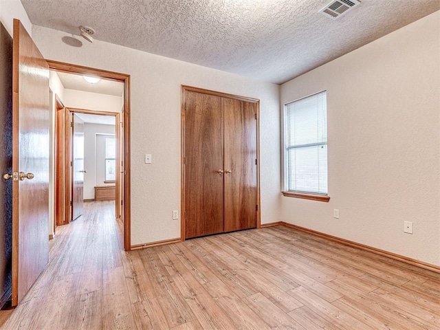 unfurnished bedroom with light hardwood / wood-style flooring, a closet, and a textured ceiling