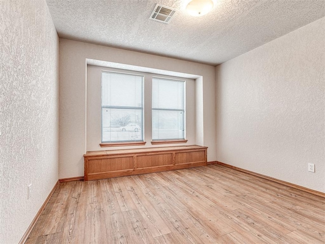 spare room featuring a textured ceiling and light hardwood / wood-style flooring