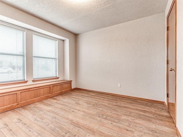 unfurnished room featuring a textured ceiling and light wood-type flooring